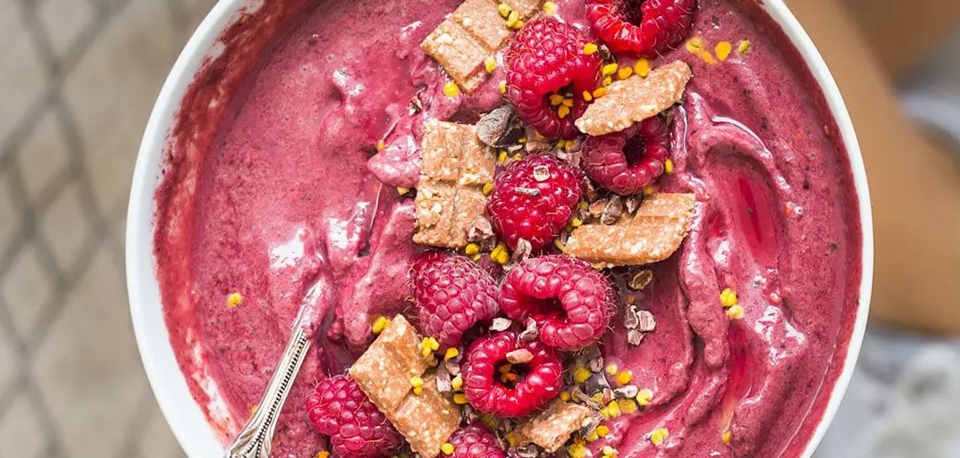 Raspberry smoothie bowl topped with fresh fruit and granola – a vibrant and healthy breakfast option