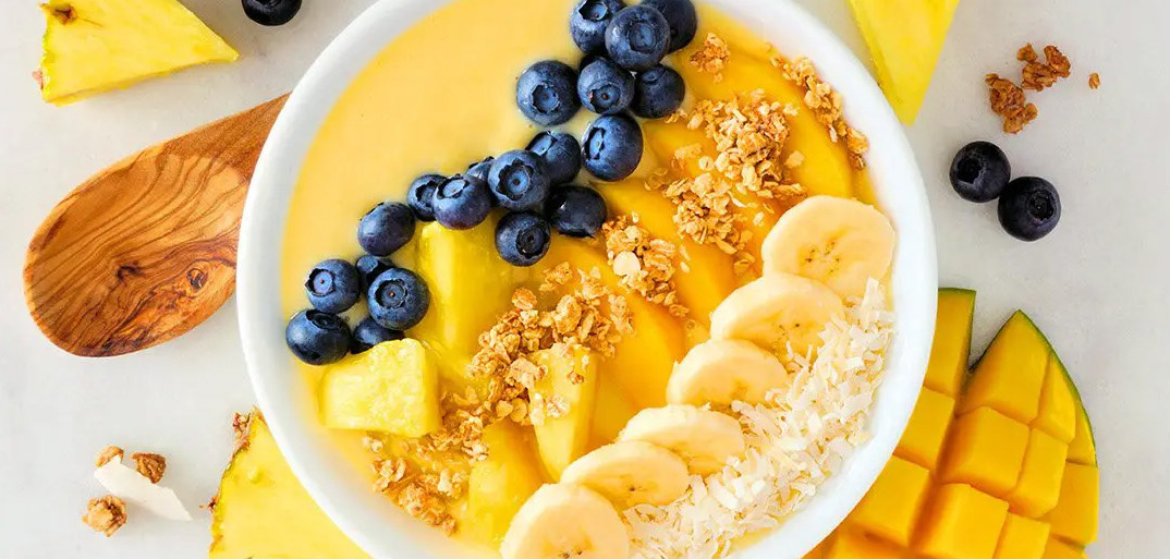 Pineapple smoothie bowl topped with fresh fruit and granola – a vibrant and healthy breakfast option