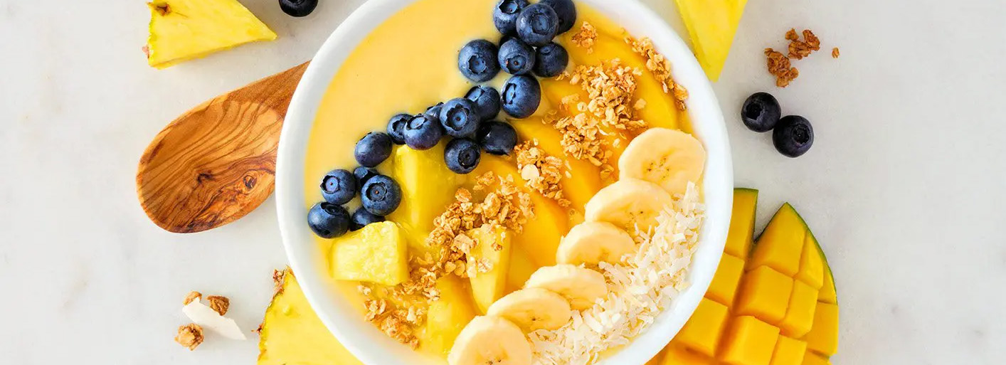 Pineapple smoothie bowl topped with fresh fruit and granola – a vibrant and healthy breakfast option