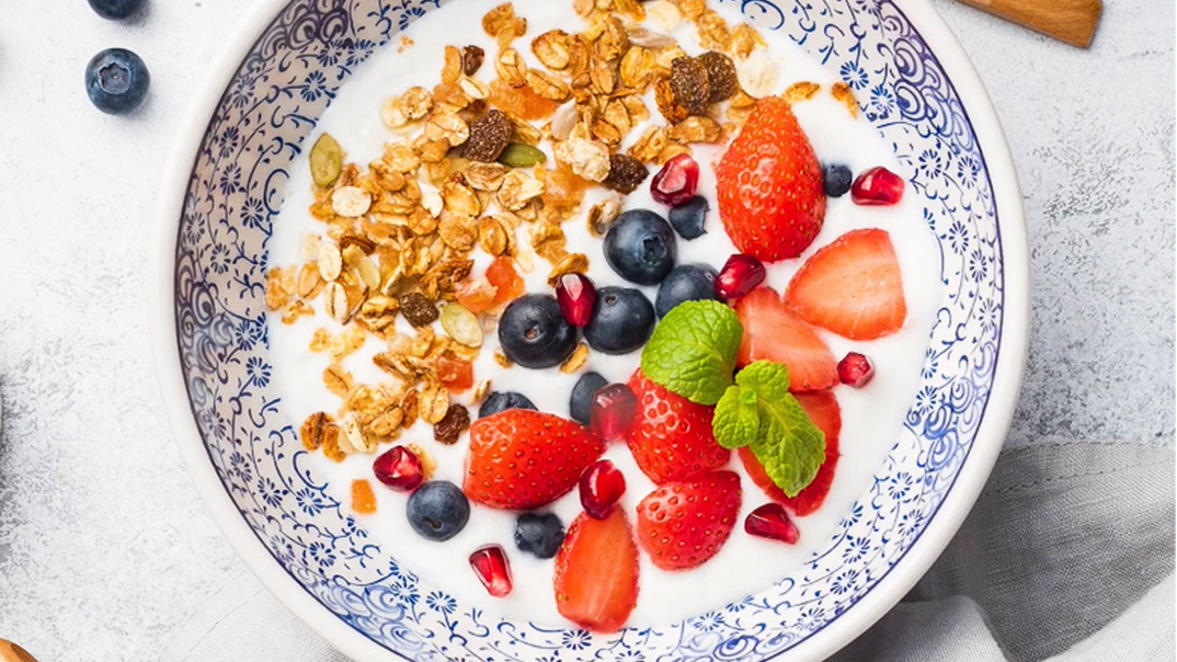 Joghurt-Bowl mit Granola, Erdbeeren, Heidelbeeren, Granatäpfeln und Haferflocken.