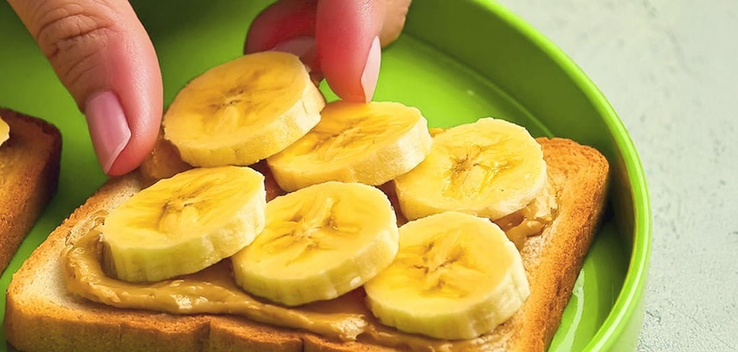 Banana toasts with fresh fruit and peanuts on a baguette – a healthy, delicious breakfast idea with natural ingredients