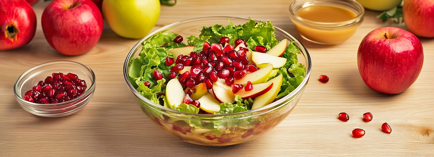 Pomegranate & Apple Salad_Header_3 Freshly baked blueberry muffins in brown paper cups, served on a plate with a bowl of blueberries in the background.